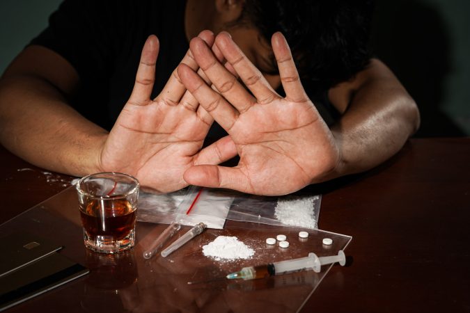 A man making a stop gesture toward substances, seeking Drug De Addiction support.